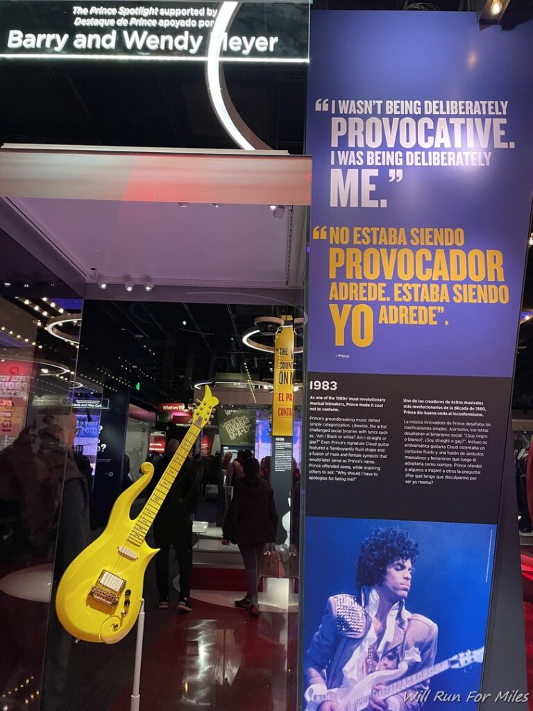 a yellow guitar in front of a sign