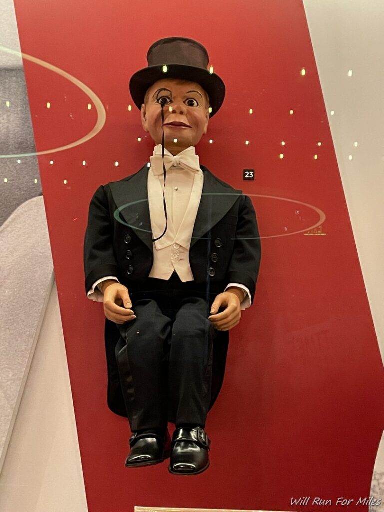 a puppet sitting on a red wall
