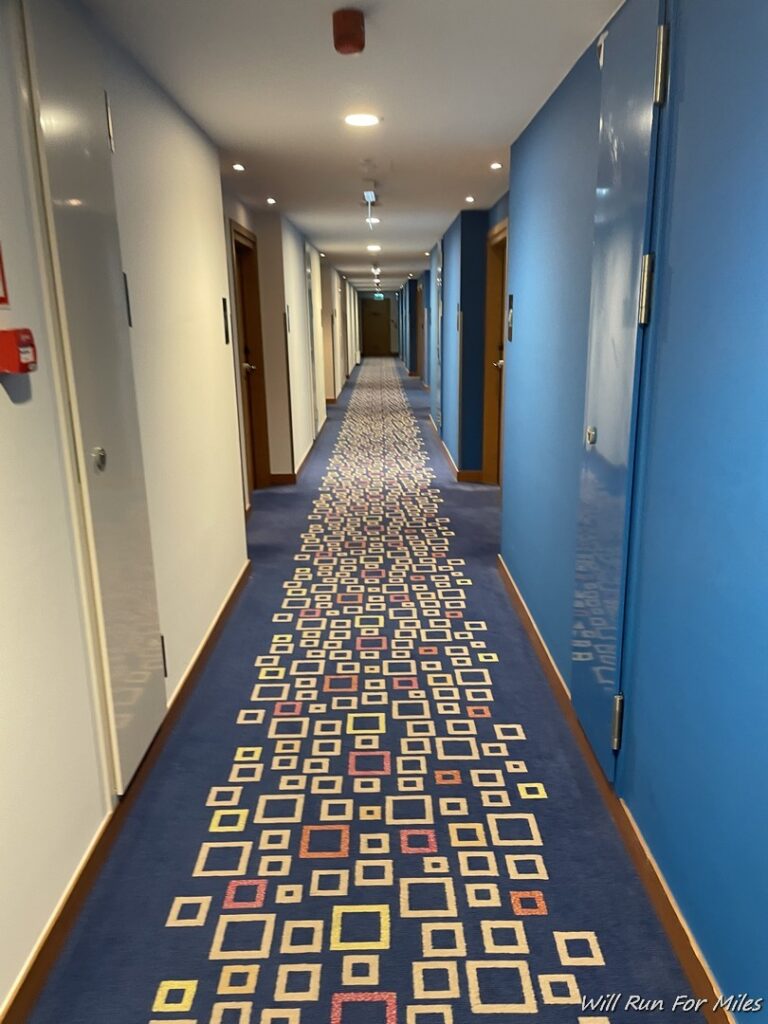 a long hallway with blue walls and a carpeted floor