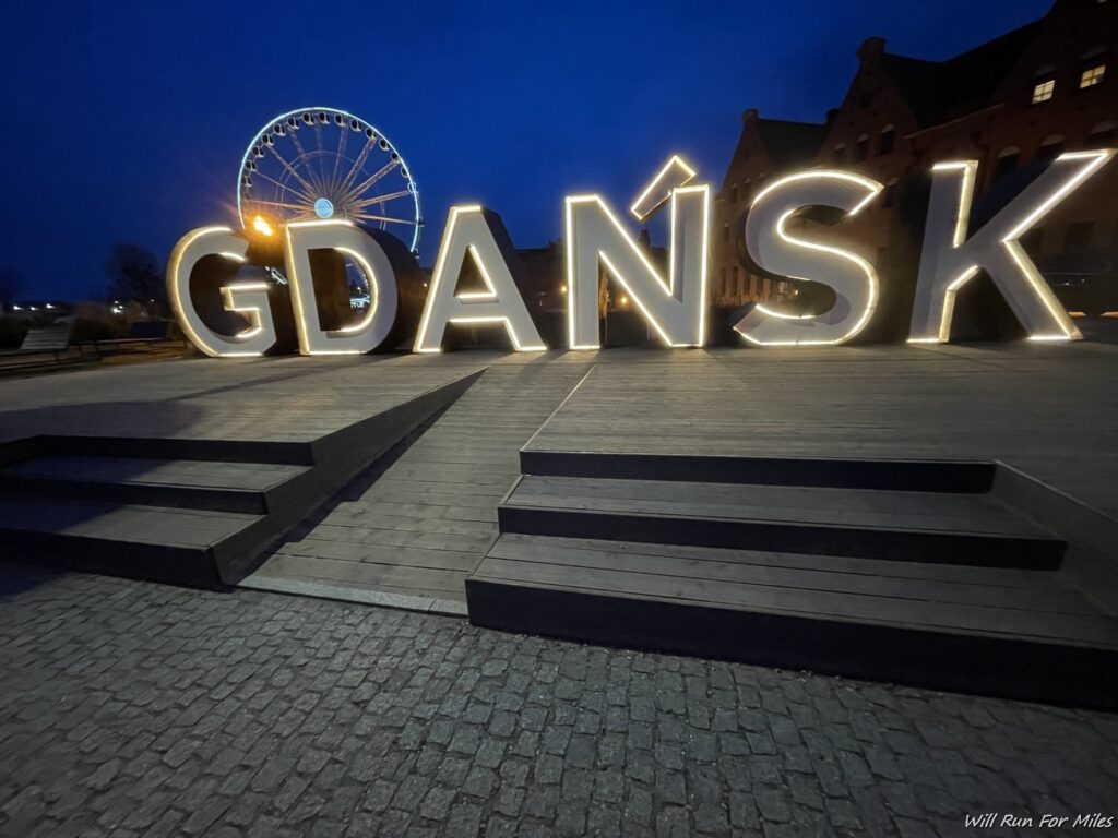 a large sign with lights in front of a ferris wheel