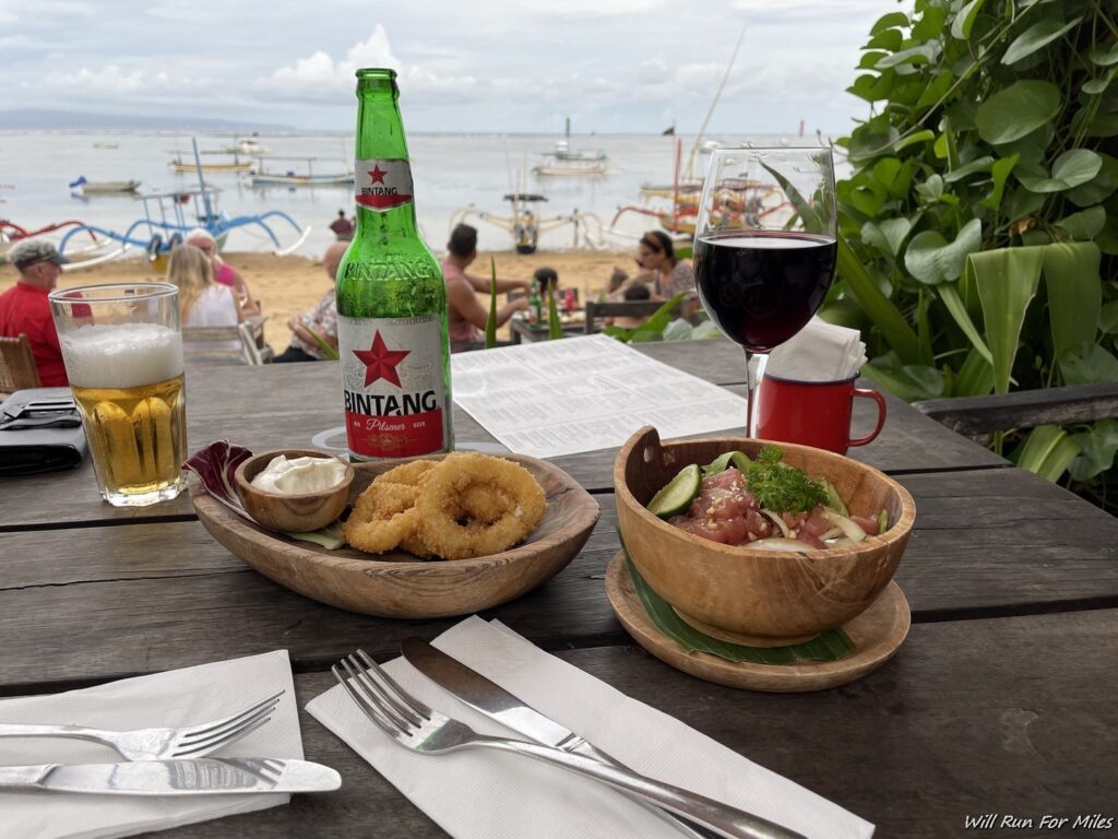 a table with food and beer on the beach