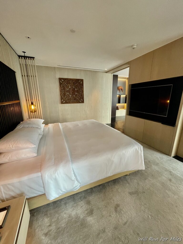 a bed with white sheets and a tv in a room