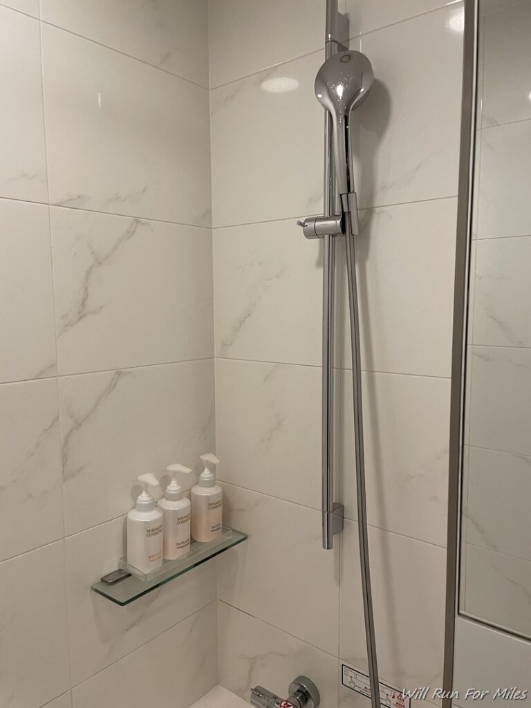 a shower with a shelf and bottles of liquid on it