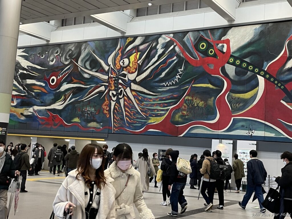 a group of people in a building with a large mural