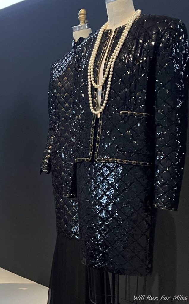 a mannequin wearing a black suit and a necklace