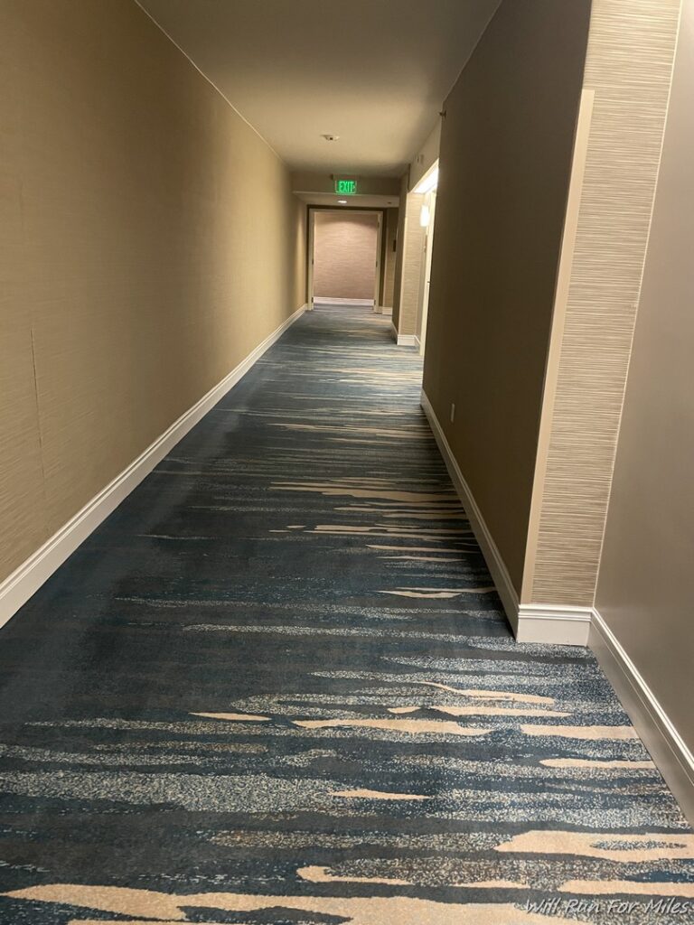 a hallway with a blue carpet and a green sign