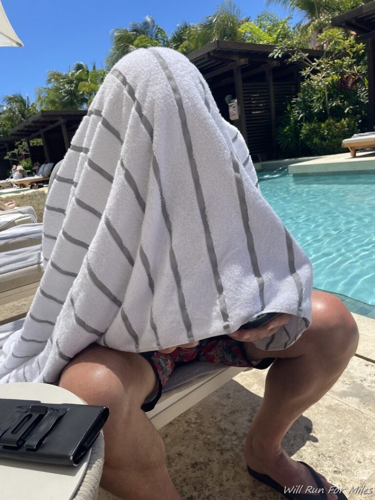 a person sitting on a lounge chair with a towel covering their face