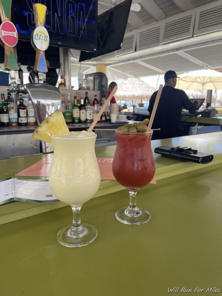 two glasses of drinks on a bar