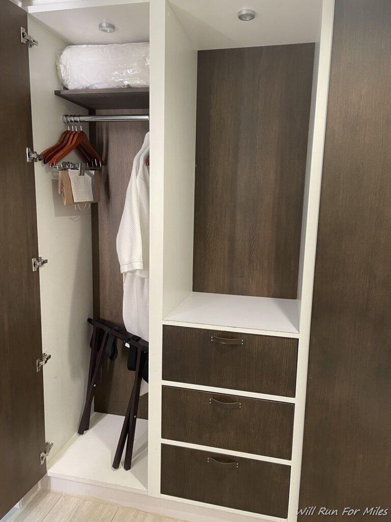 a closet with a white robe and a shelf