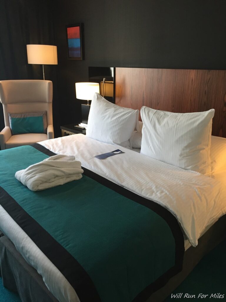a bed with white pillows and a green blanket