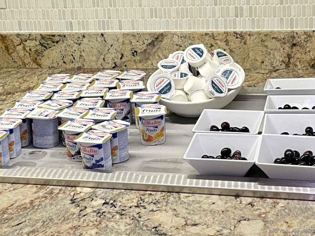 a group of yogurt containers and bowls of fruit
