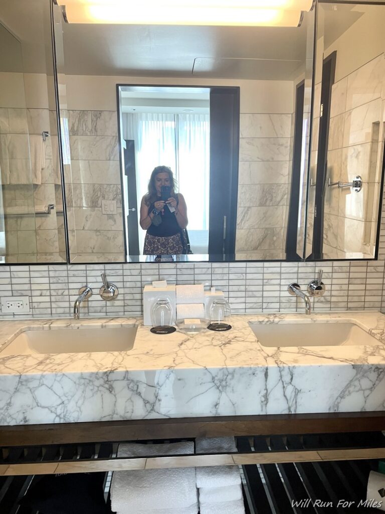 a woman taking a picture of a bathroom sink