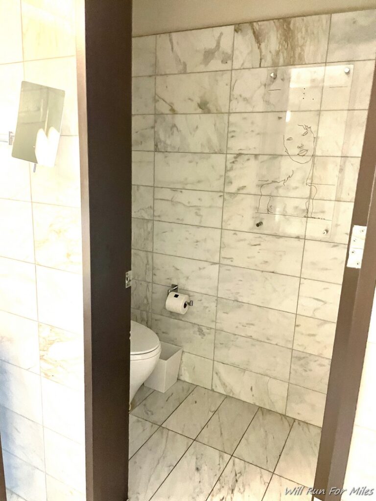 a bathroom with a toilet and a tile wall