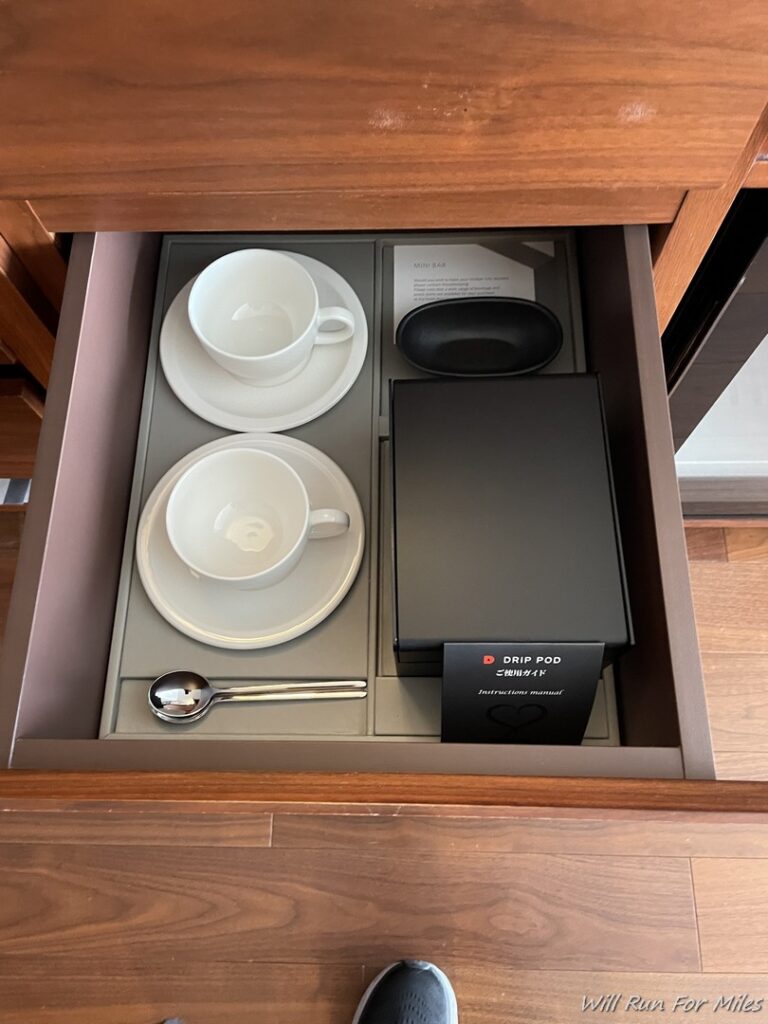 a drawer with a tray of teacups and saucers