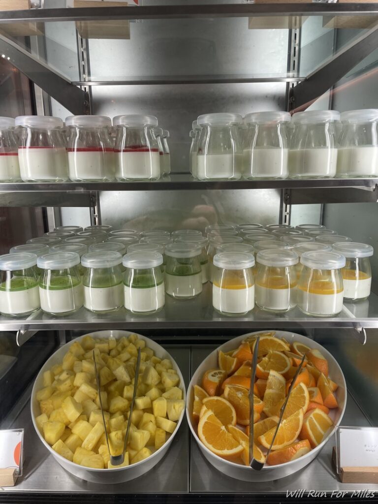 a shelf with bowls of fruit and yogurt