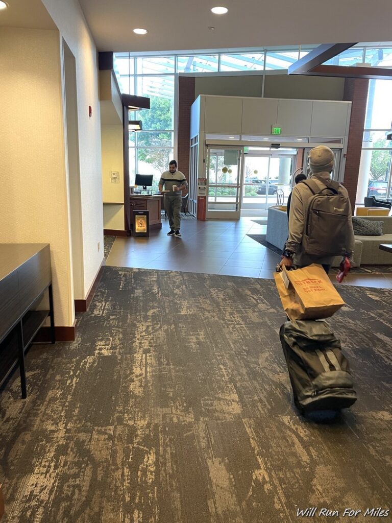 a man with a backpack pulling a luggage bag in a hotel lobby