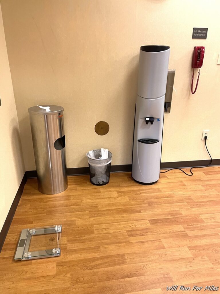 a water cooler and trash can on a wood floor