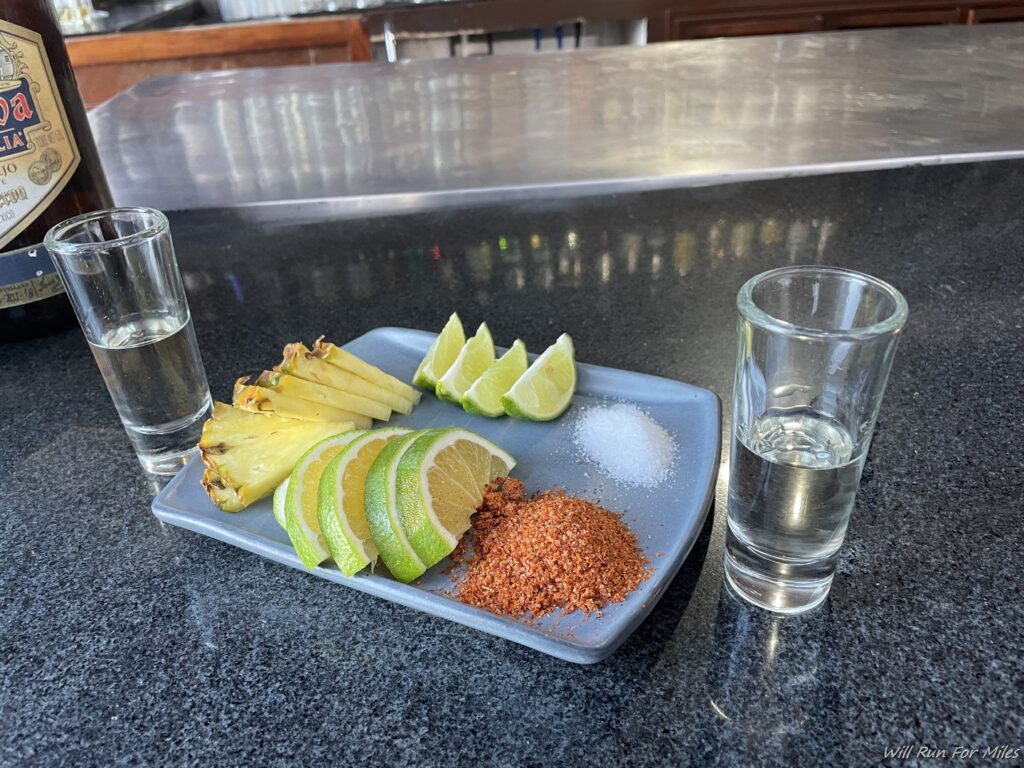 a plate of food and two shot glasses on a counter