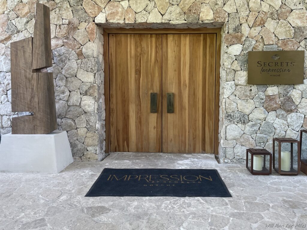 a door with a black mat and a sign on the wall