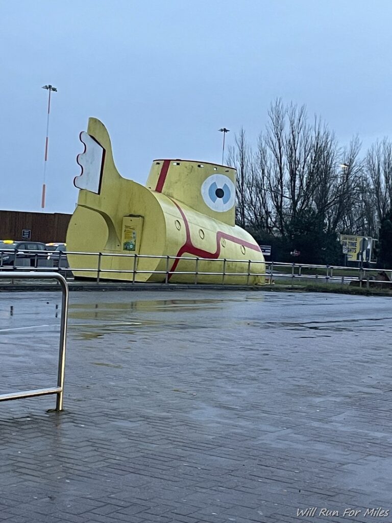 a yellow submarine statue on a wet road