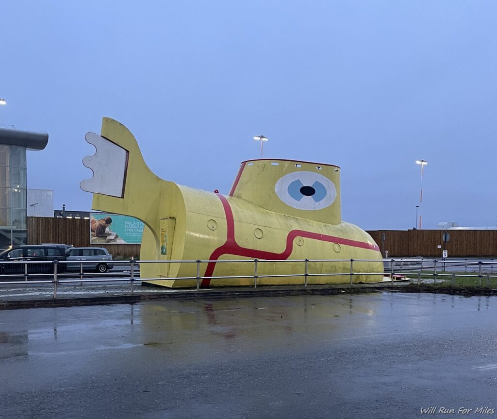a yellow submarine statue in a parking lot