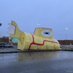 a yellow submarine statue in a parking lot