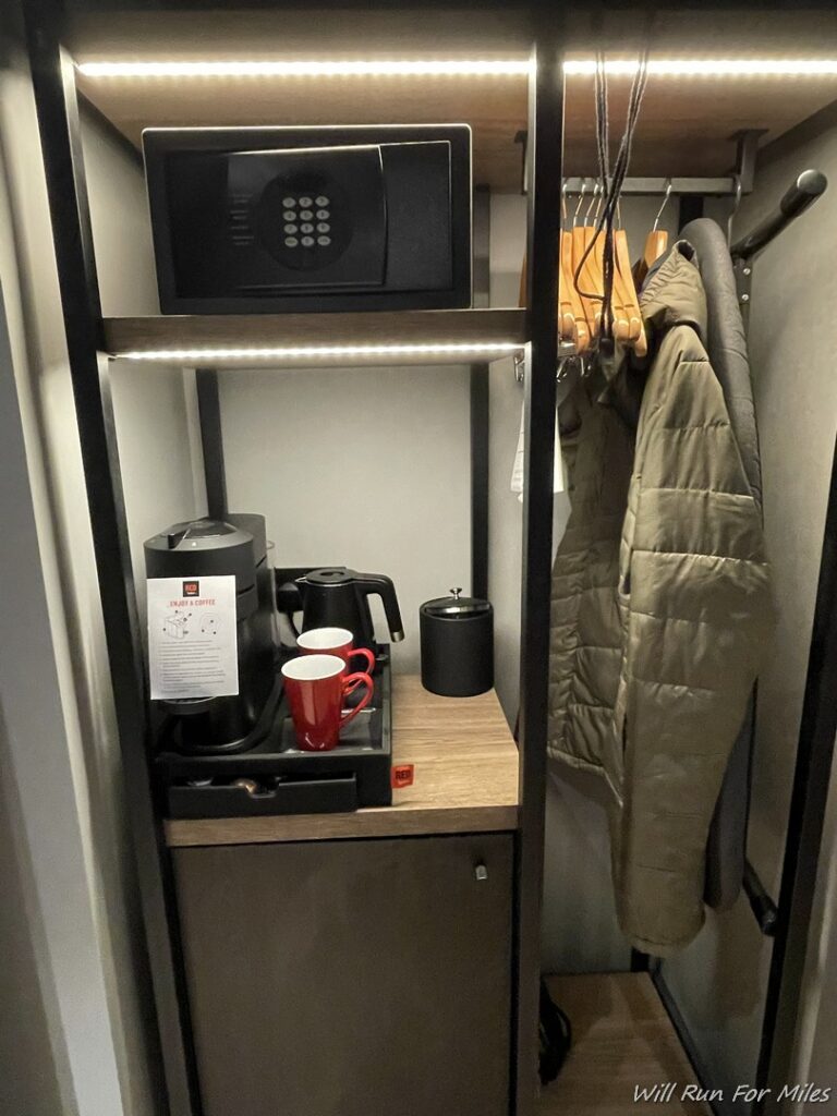 a shelf with a microwave and coffee cups