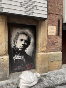 a dog lying on the ground next to a door with a painting of a man