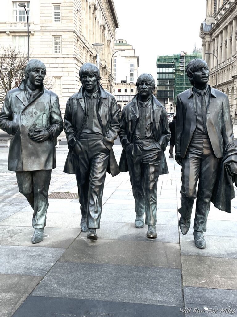a group of statues of men walking on a sidewalk