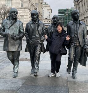 a woman standing next to a statue of a group of people