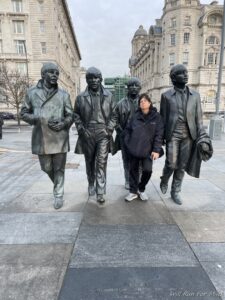 a woman standing next to a statue of a group of people