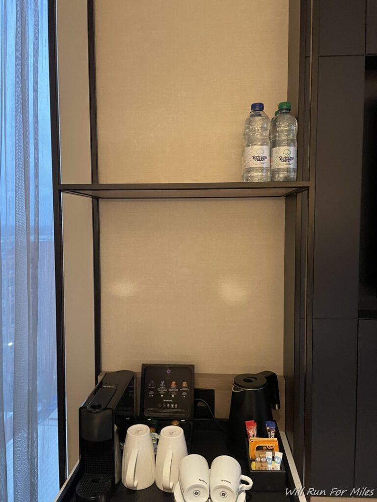 a shelf with coffee cups and water bottles