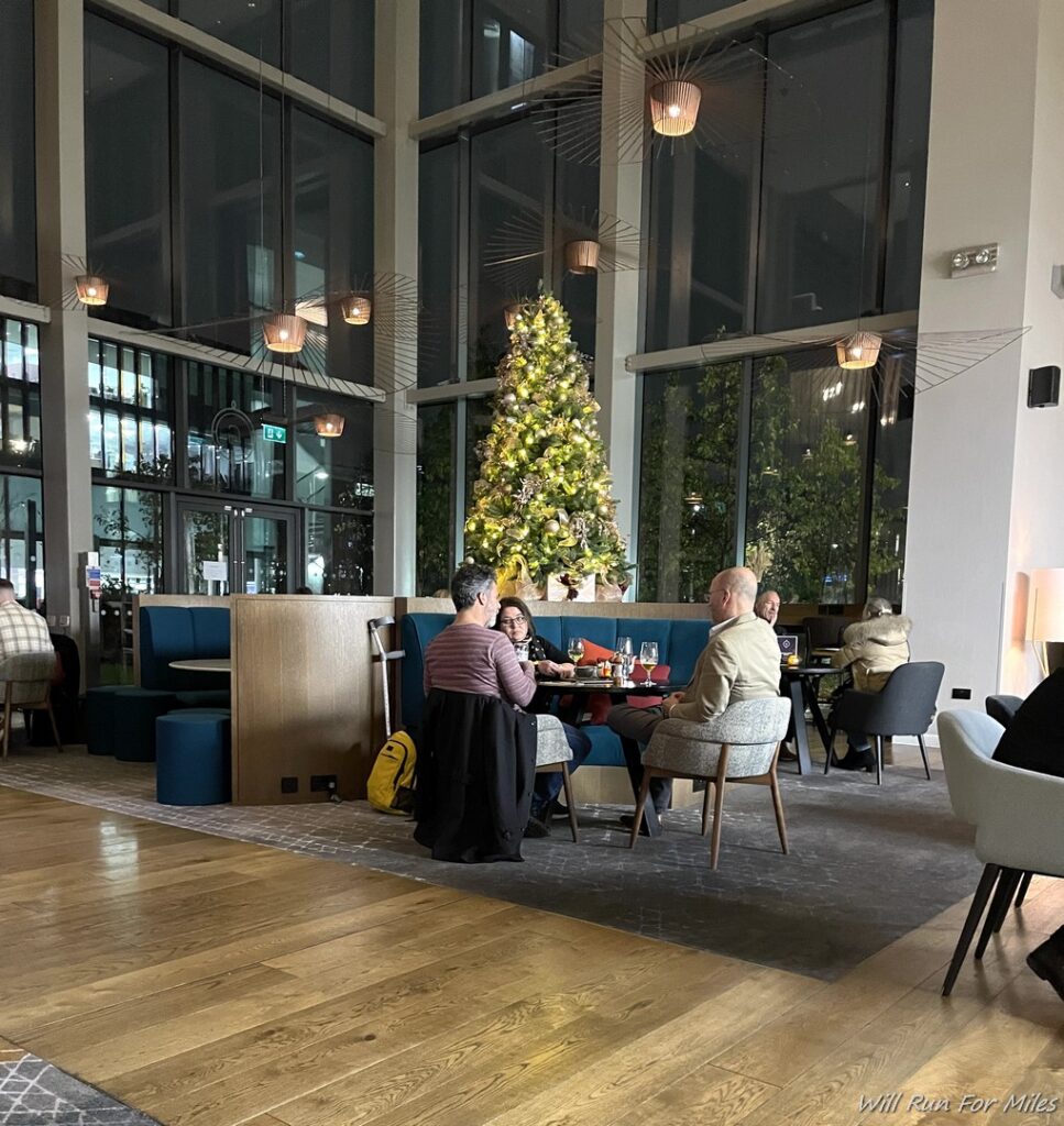 a group of people sitting at a table in a room with a christmas tree