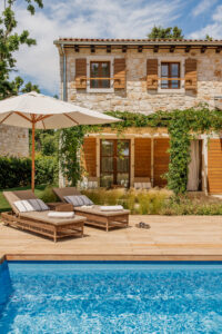 a pool with lounge chairs and umbrella by a building