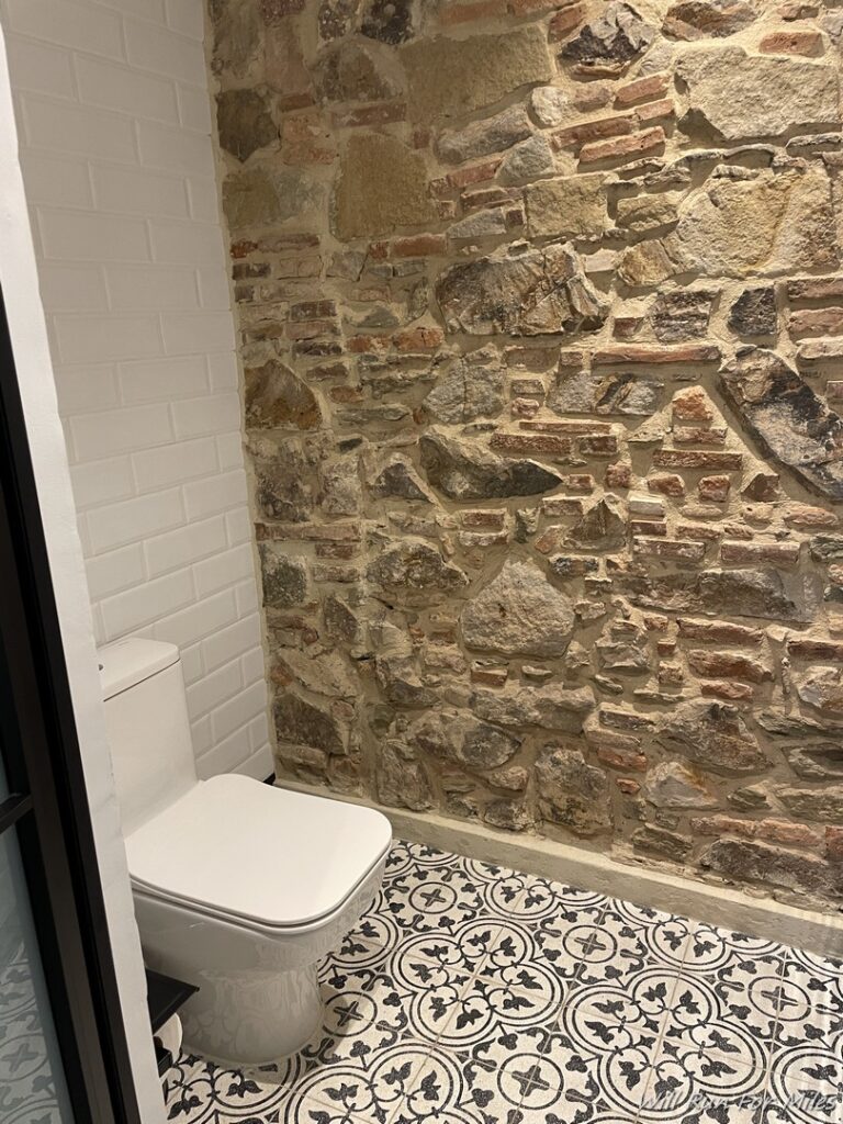 a bathroom with a stone wall and toilet