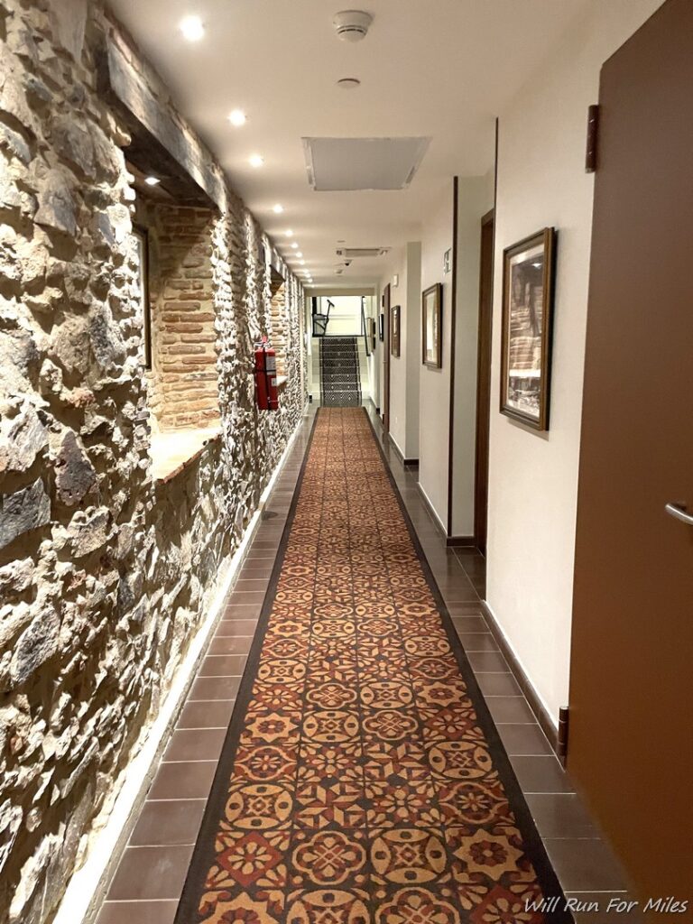 a long hallway with a stone wall and a tile floor
