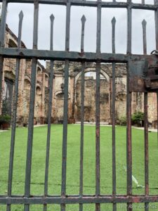 a gate with a green grass field and a brick building