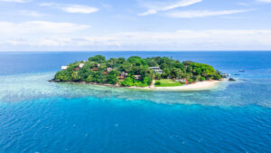 an island with trees and houses in the middle of the ocean