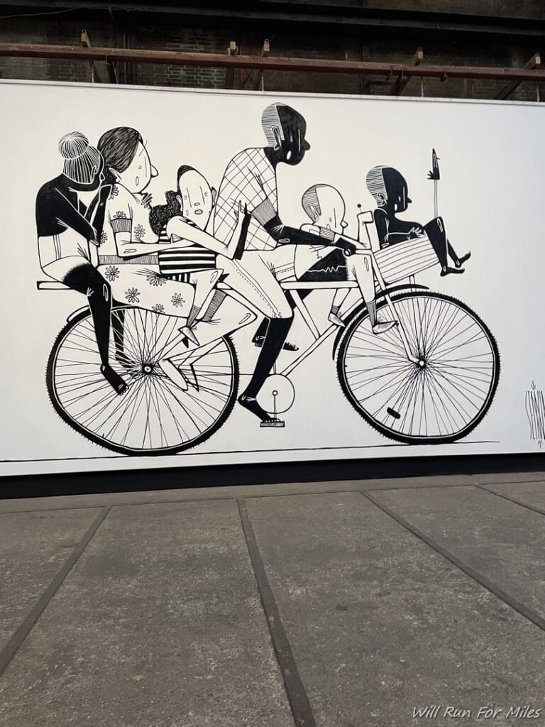 a large black and white picture of people riding a bicycle