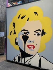 a painting of a woman with yellow hair and black eye