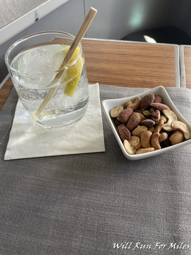 a bowl of nuts and a glass of water with a lemon slice