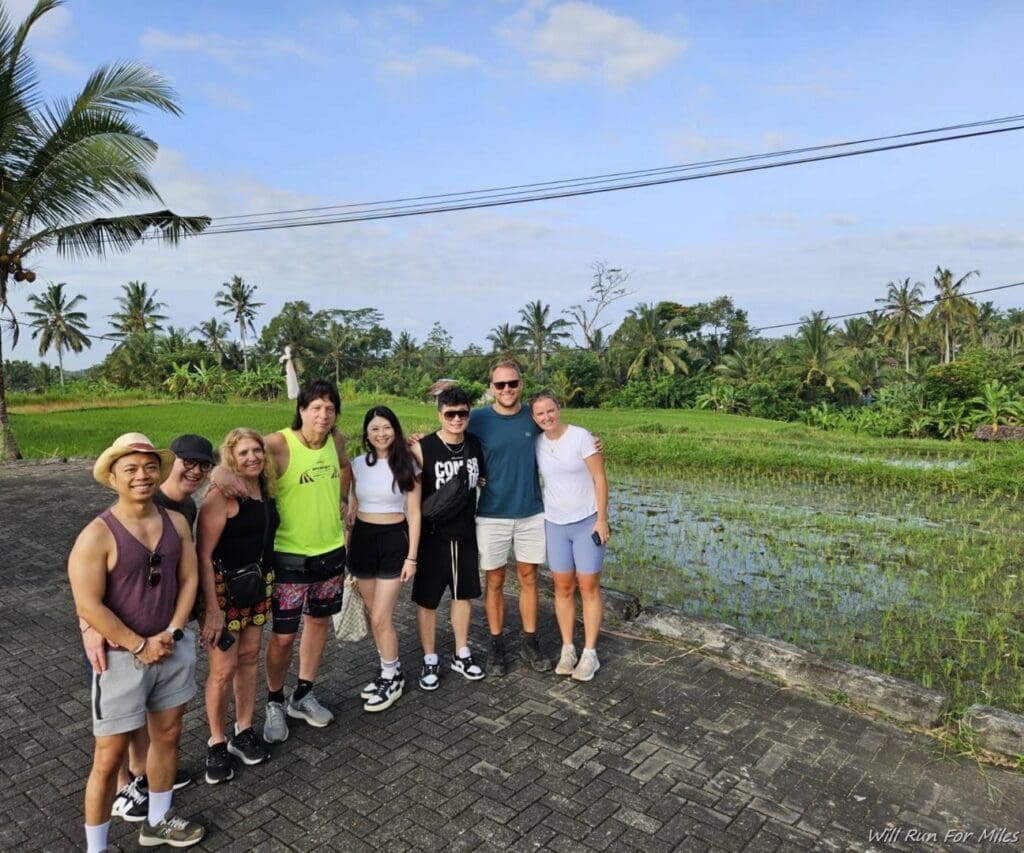 a group of people standing on a brick path with water and trees