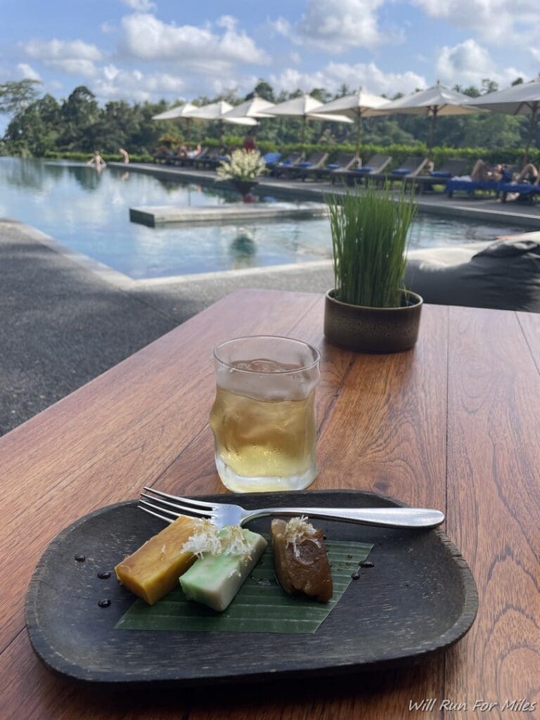 a plate of food on a table with a drink and umbrellas in the background