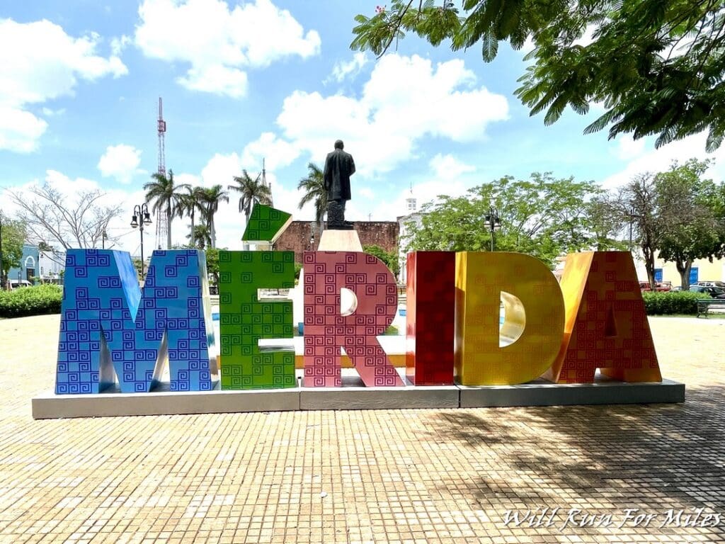 a colorful sign with a statue in the background