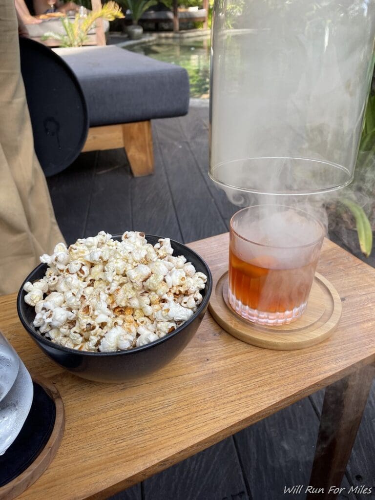 a bowl of popcorn and a glass of liquid on a table