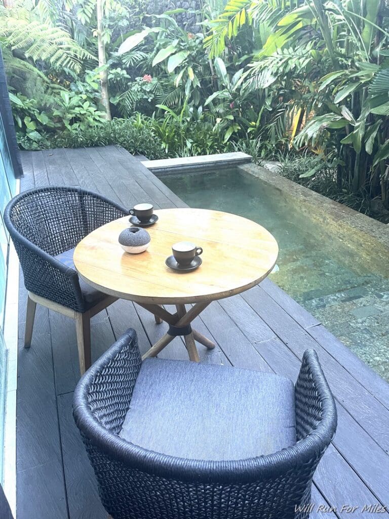 a table and chairs on a deck with a pool in the background