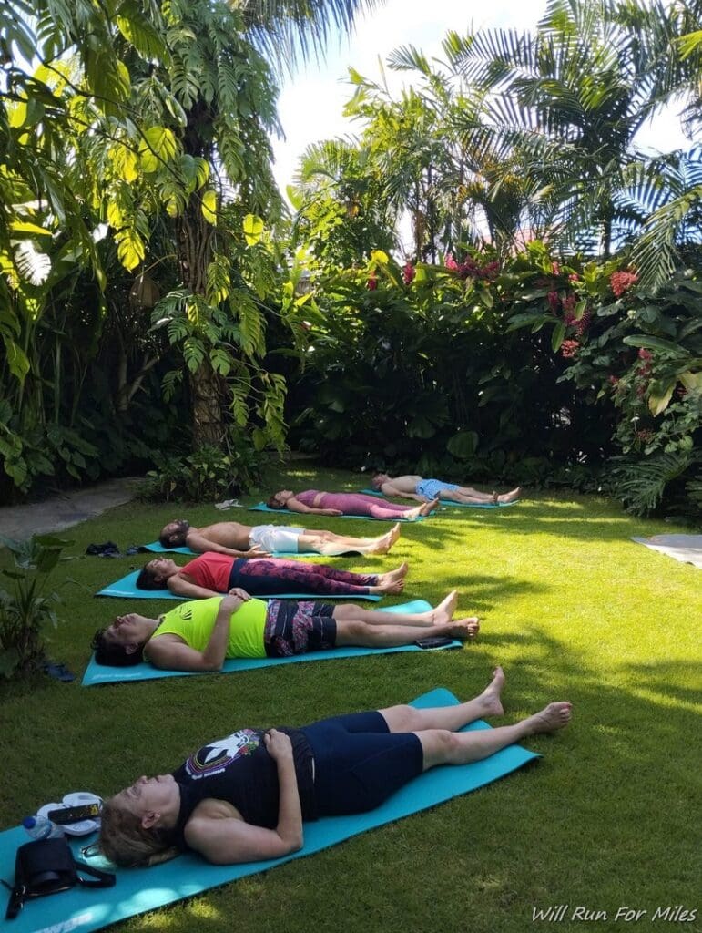 a group of people lying on mats in a garden