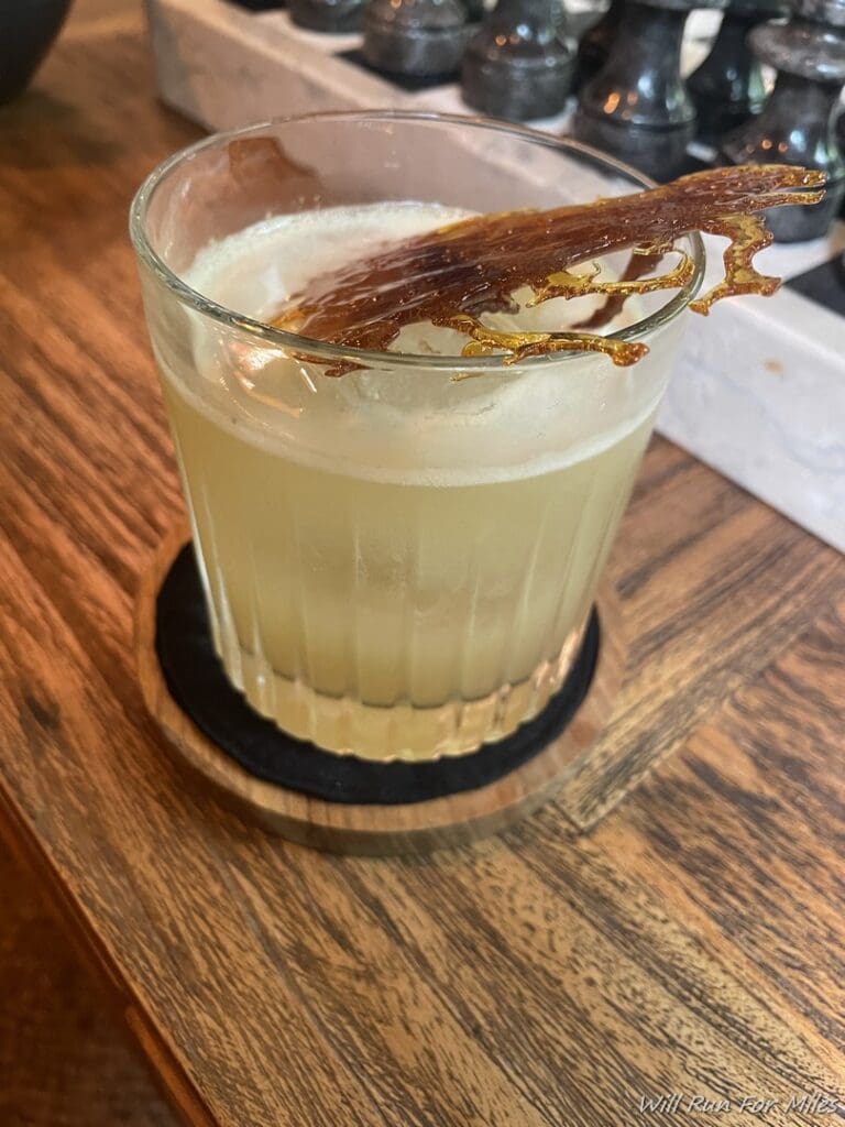 a glass of liquid with a piece of bacon on top