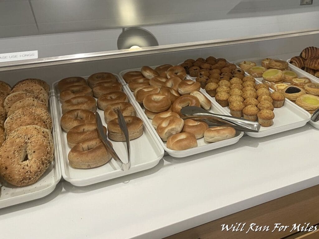 trays of bagels and muffins on a counter