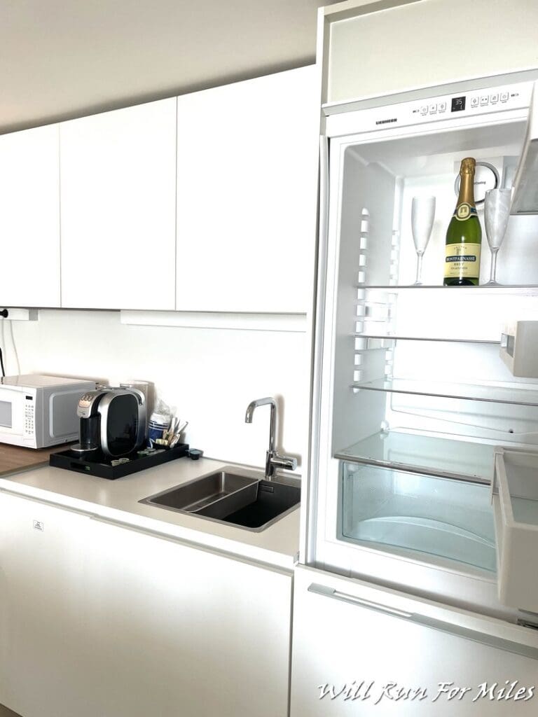 a white kitchen with a refrigerator and a bottle of wine